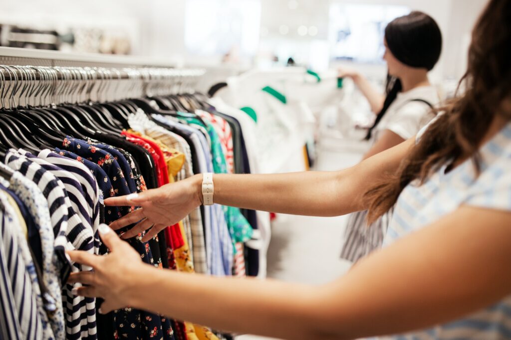 Two young smiling slim girls with long dark hair,wearing casual style,have shopping in a modern mall